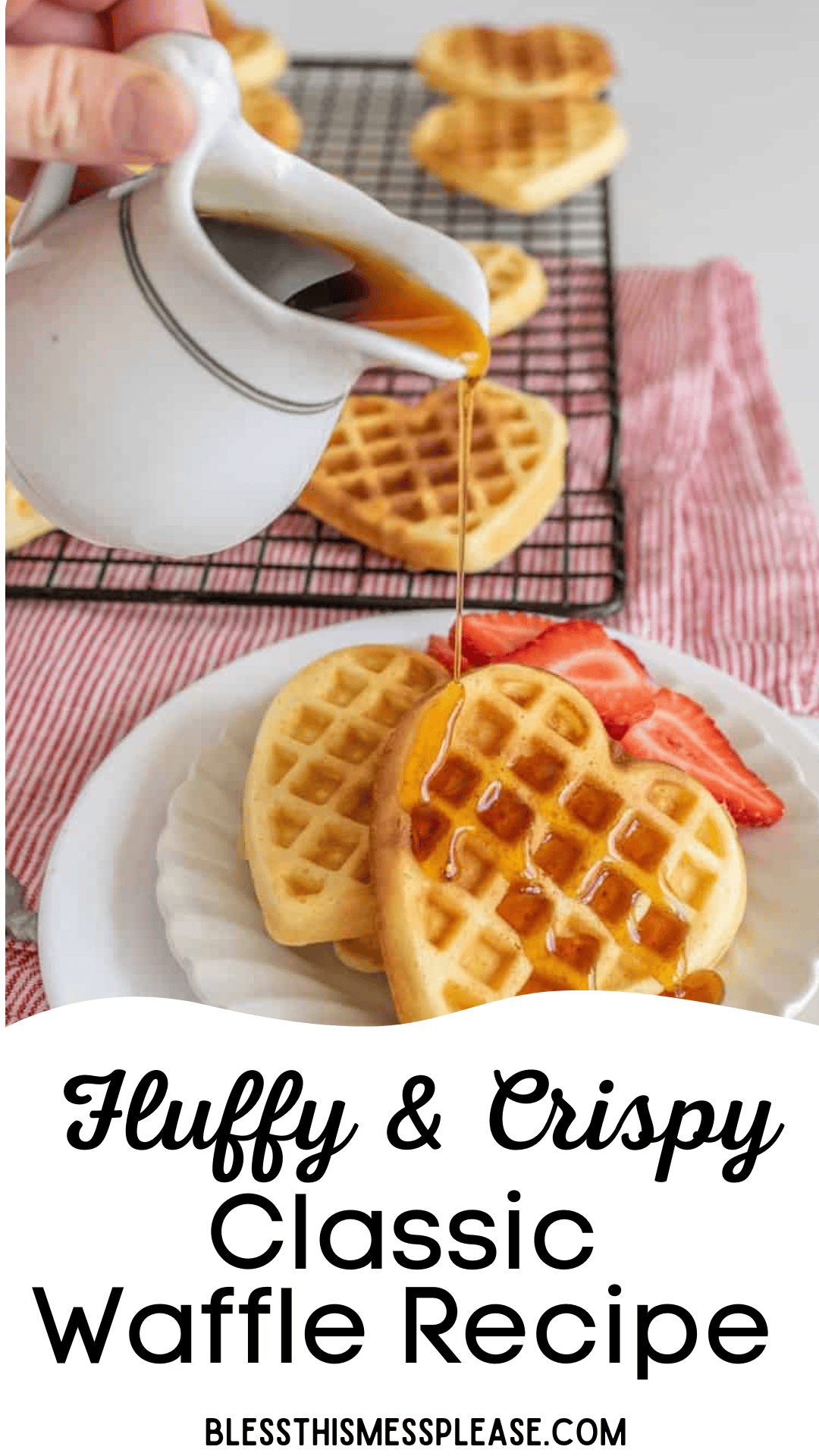 Drizzling syrup over heart-shaped waffles adorned with strawberry slices, with more classic waffles cooling on a rack in the background. Text below reads Fluffy & Crispy Classic Waffle Recipe.