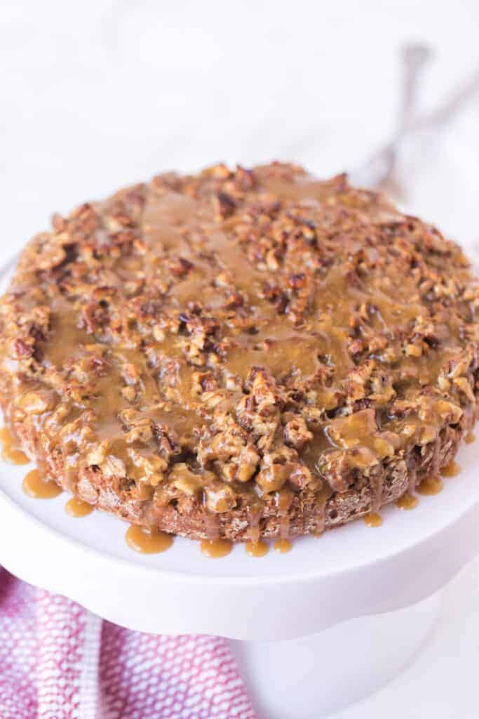oatmeal cake with sticky nut icing on top of a white cake stand