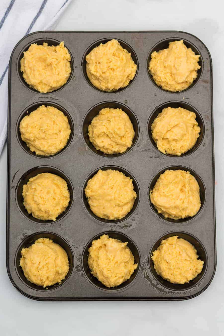 Maïsmuffinbeslag in een muffinpan die wacht om in de oven te gaan.
