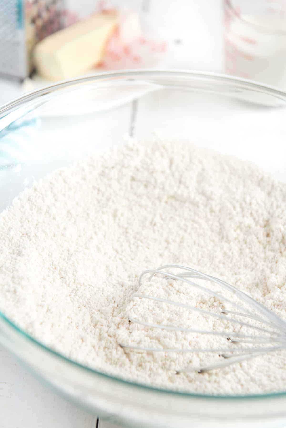 whisking flour in a clear glass mixing bowl