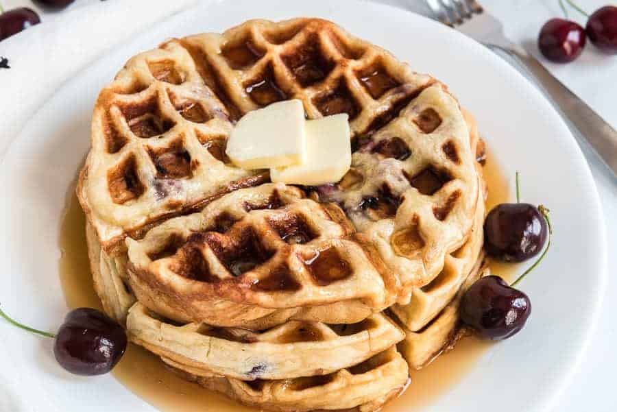 sweet cherry waffles with butter on top on a white plate