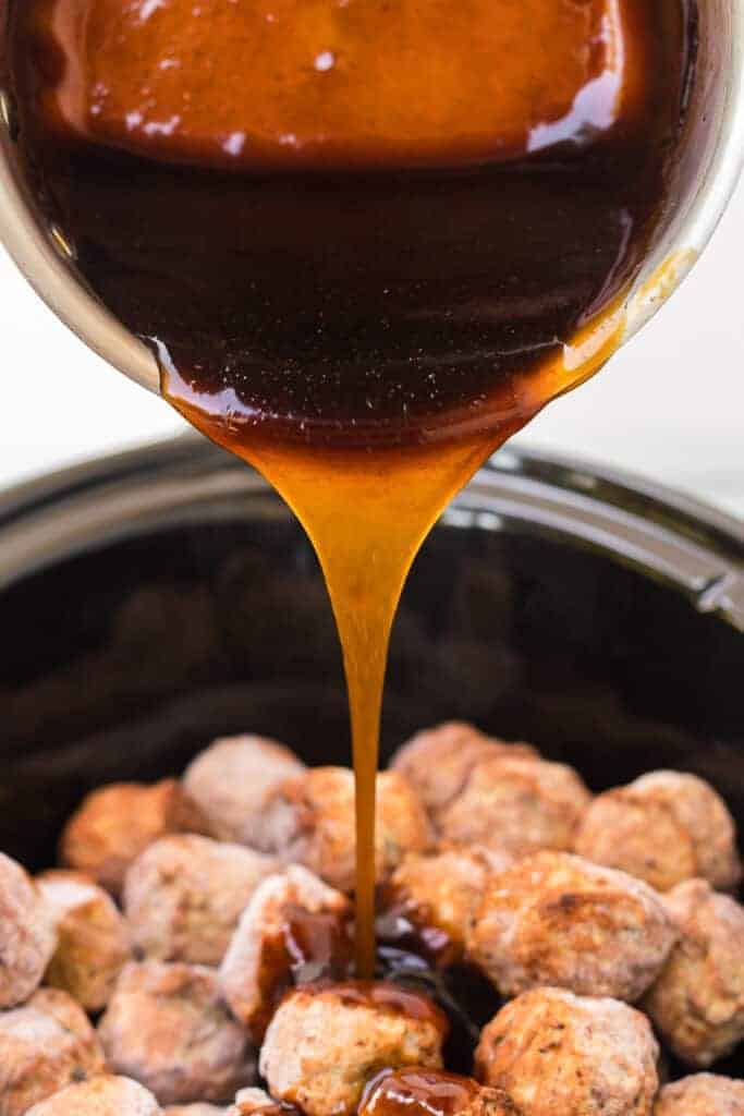slow cooker with meatballs with honey teriyaki sauce dripping on them