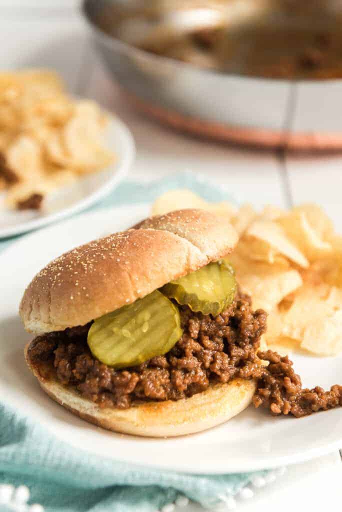 sloppy joe on a plate with pickles and chips