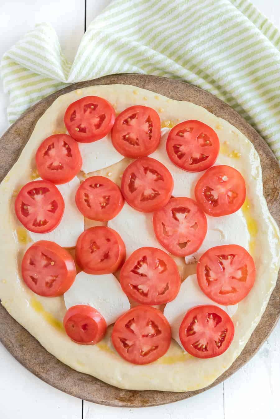 tomatoes and mozzarella on raw margarita pizza.
