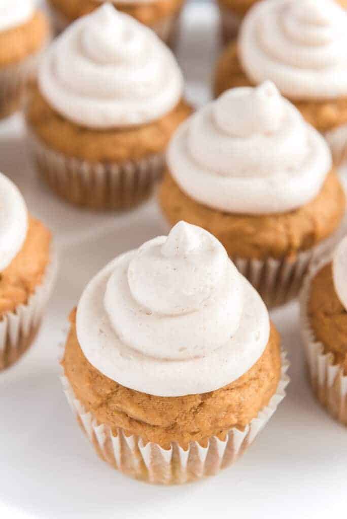 light golden pumpkin cupcakes with a cream colored and cinnamon speckled icing