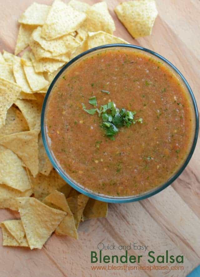 top view of a bowl of blender salsa with a pile of yellow tortilla chips to the left