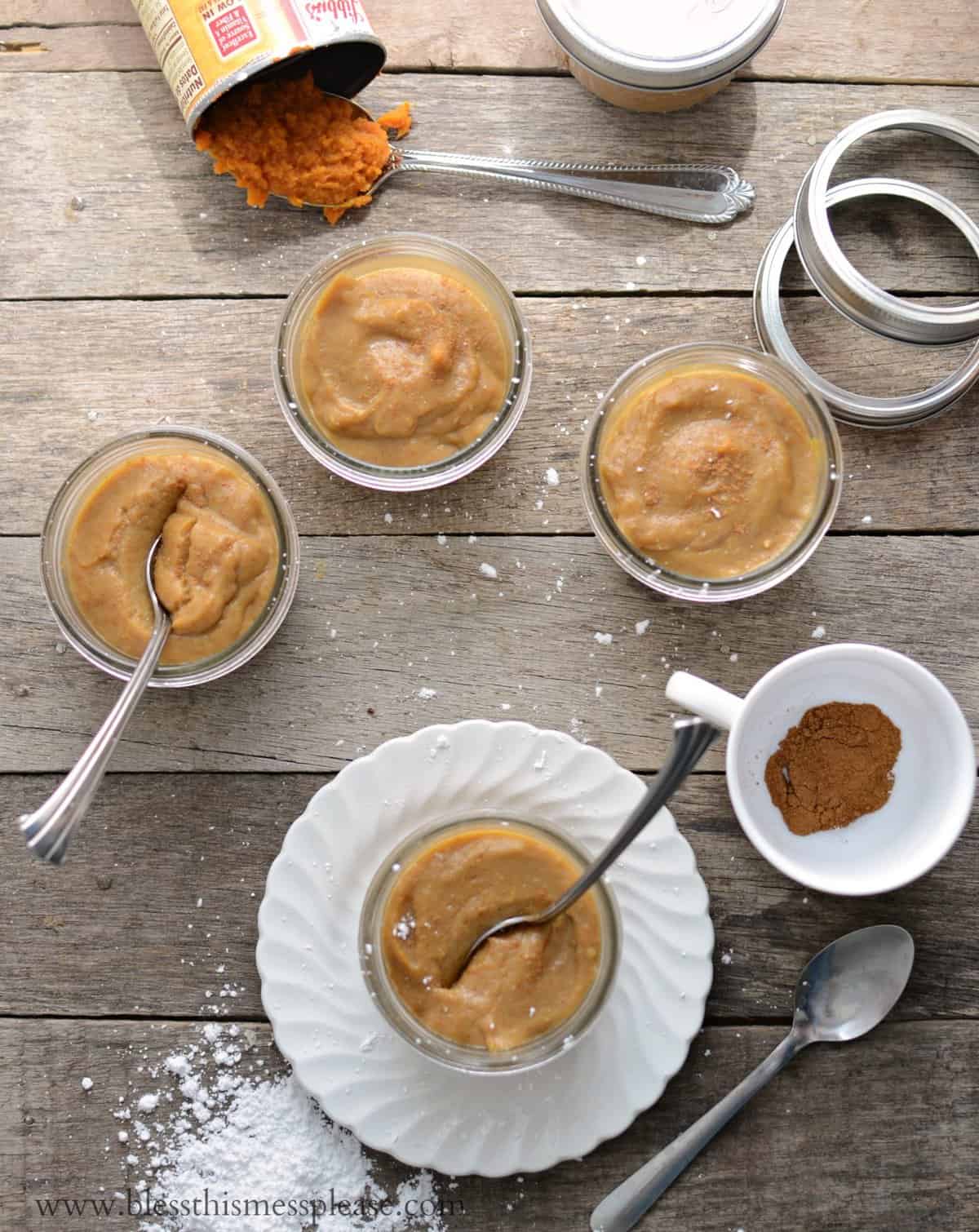 pumpkin pudding in small glass jars on wooden table.