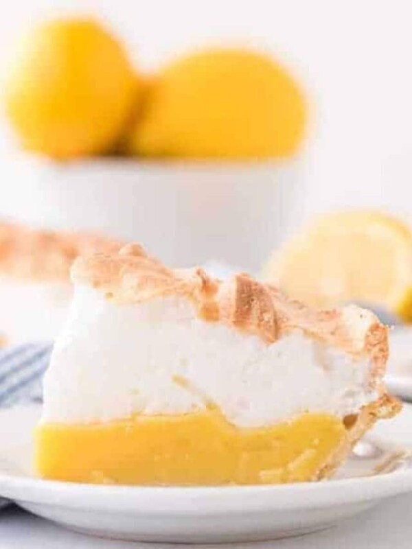 closeup of lemon meringue pie slice on round white plate