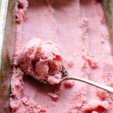 a cold pan of strawberry frozen yogurt and a spoon conelling it