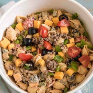 white bowl with potato salad with tomatoes peppers and olives inside