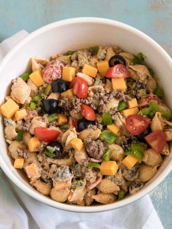 white bowl with potato salad with tomatoes peppers and olives inside