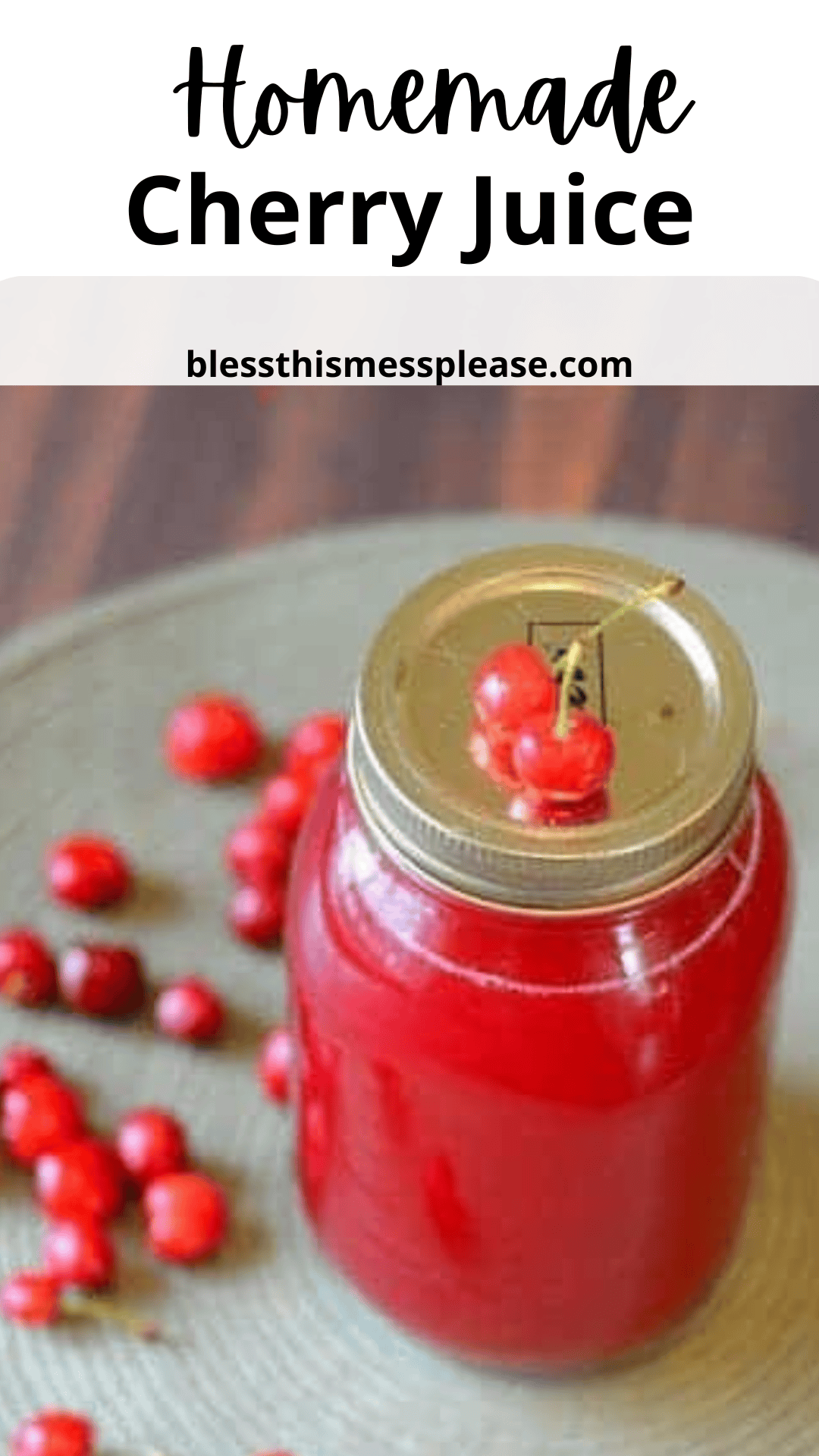 A jar of homemade cherry juice with a gold lid, garnished with fresh cherries, graces a wooden surface. Scattered cherries lie beside it. The words Homemade Cherry Juice and blessthismessplease.com float above, celebrating this delightful creation.