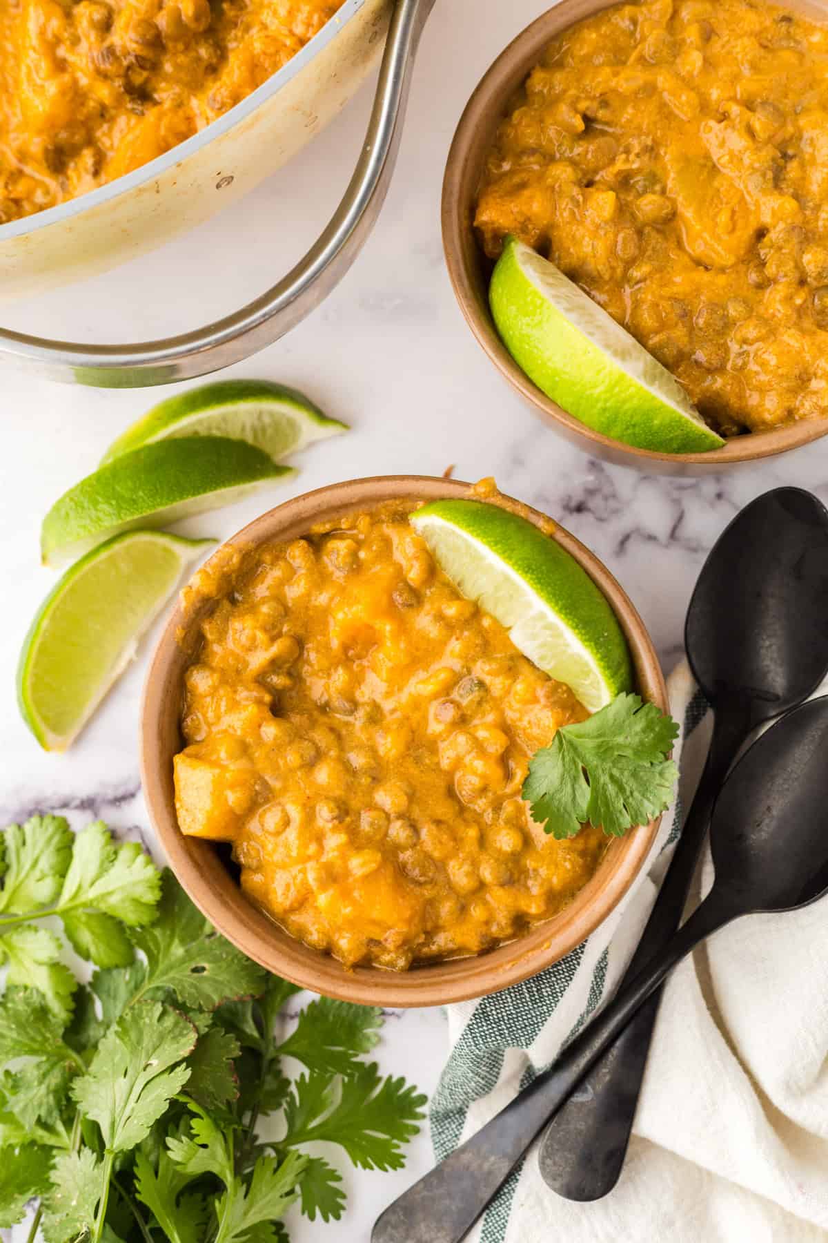 lentil curry finished and in a bowl garnished with limes.