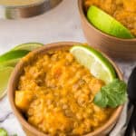 wooden serving bowl with Lentil curry with butternut squash and limes.