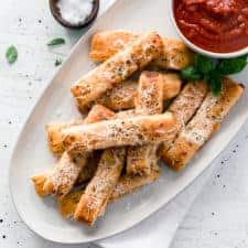 Plate of cheesy pizza sticks and cup of sauce