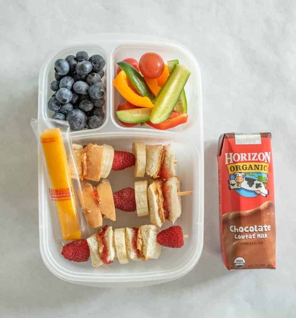 School supplies and lunch box with sandwich and vegetables. Back