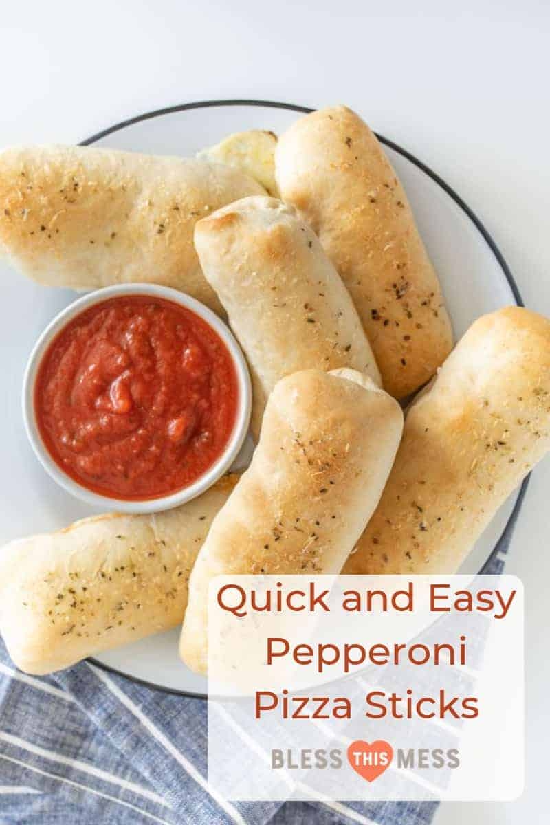 breadsticks on a white plate with a small bowl of red marinara sauce on a blue and white striped towel.