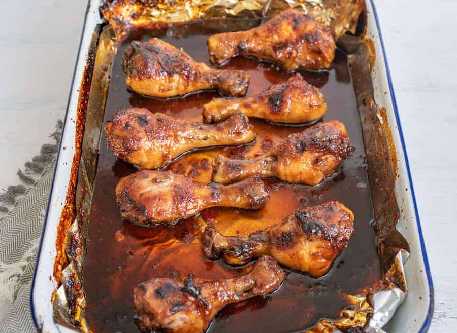 chicken legs on a sheet pan with sauce.