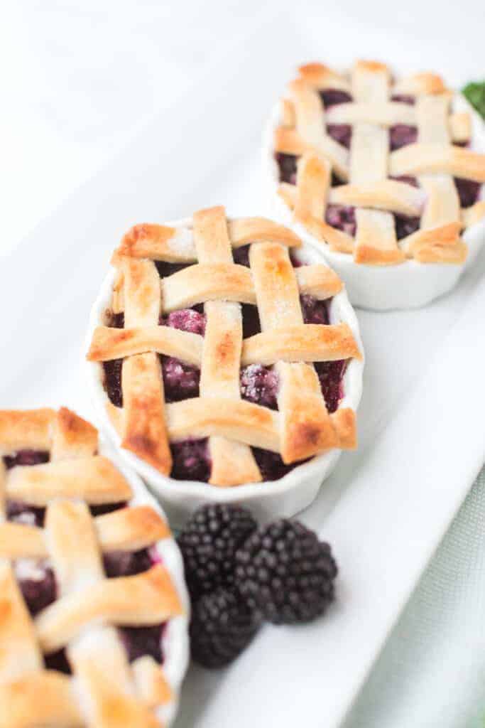 small white dishes filled with blackberry pie filling and a lattice crust top