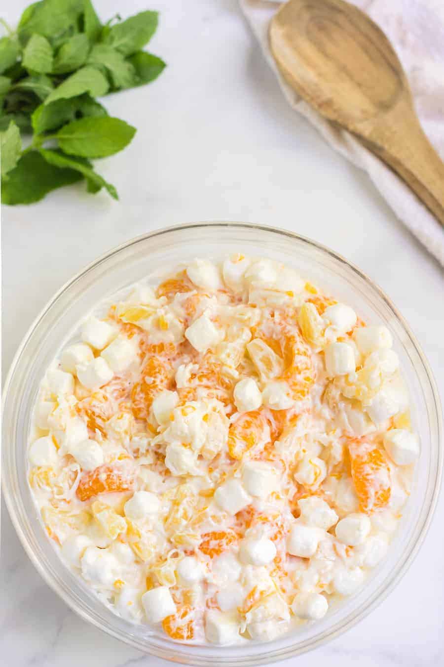 6 cup salad with oranges marshmallows and a cream fruit salad mix in a glass mixing bowl