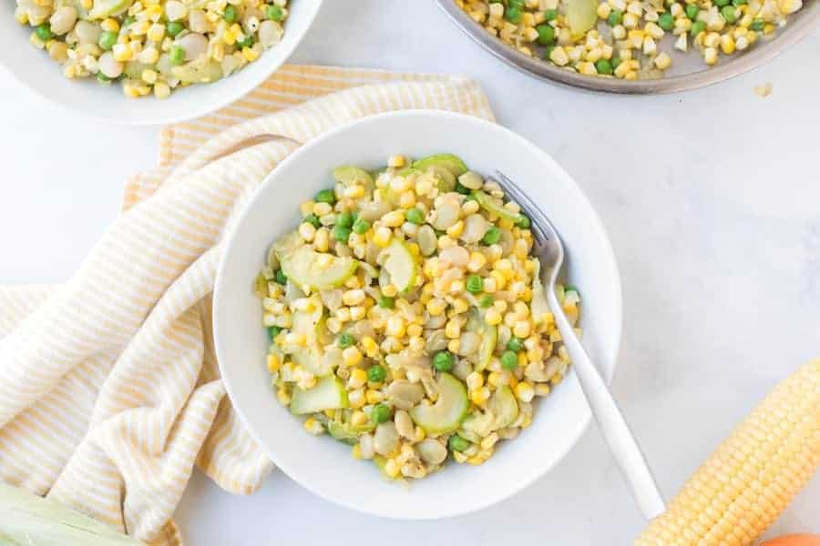 corn, squash, and bean side dish in a pot and white bowl.