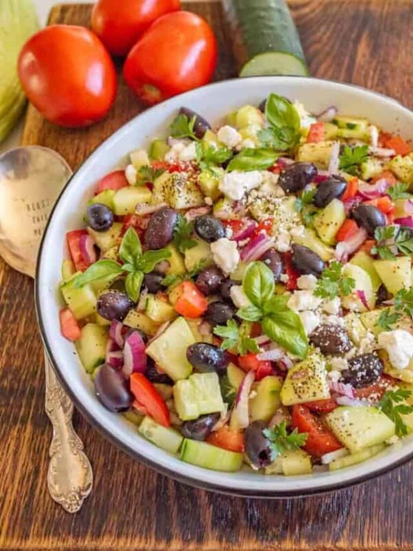 cucumber and tomato salad with olives and basil in a white bowl