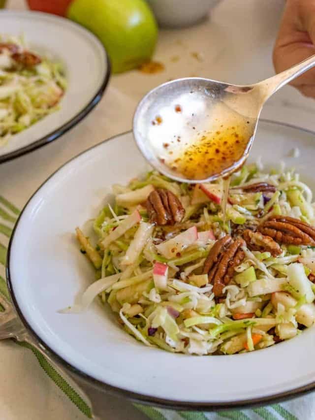 cabbage and apple salad with walnuts and a big silver spoon.