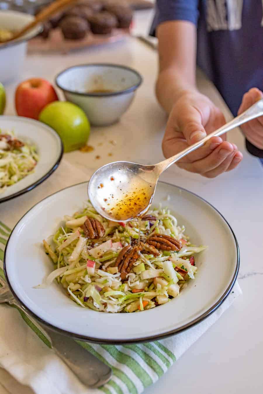 cabbage and apple salad with pecans and a big silver spoon.