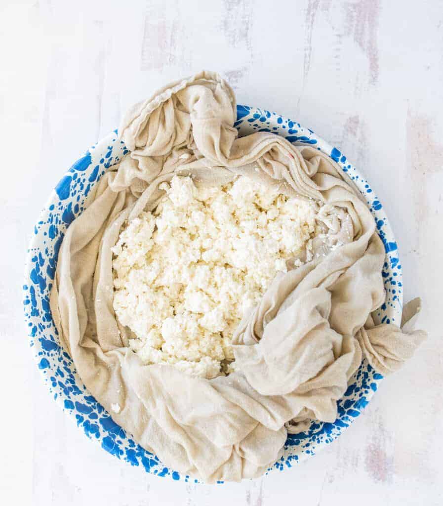 cottage cheese in a cheese cloth on a blue speckled plate
