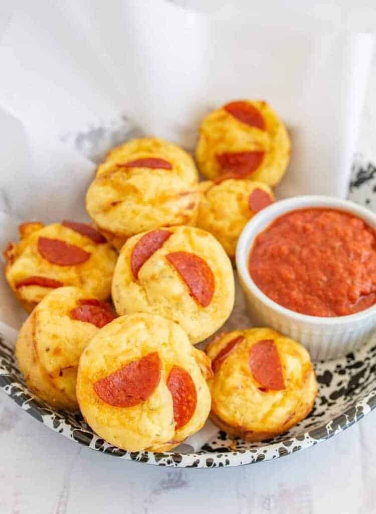 pizza bites with marinara dipping on parchment in a bowl