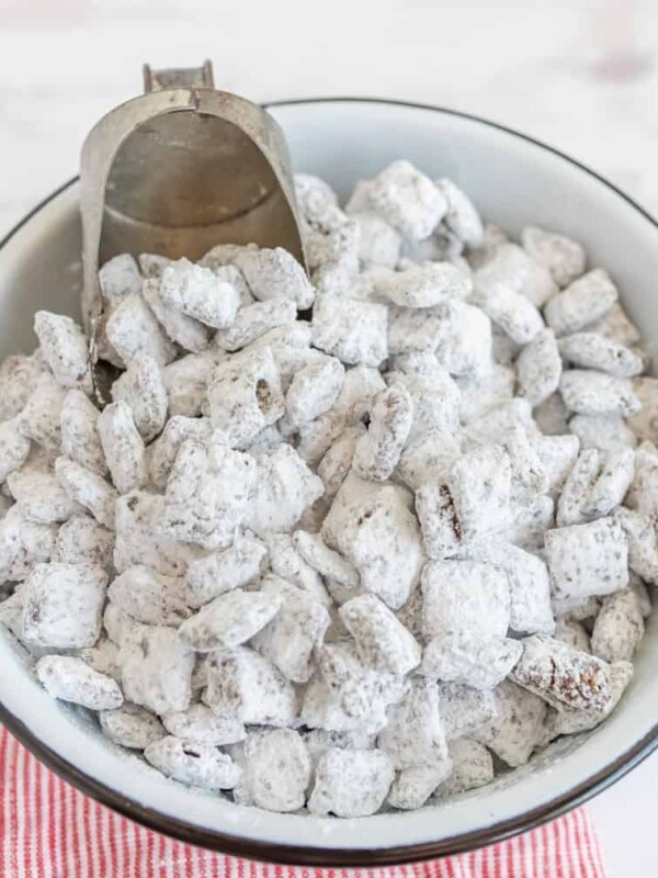 a white bowl of lightly white dusted chex mix