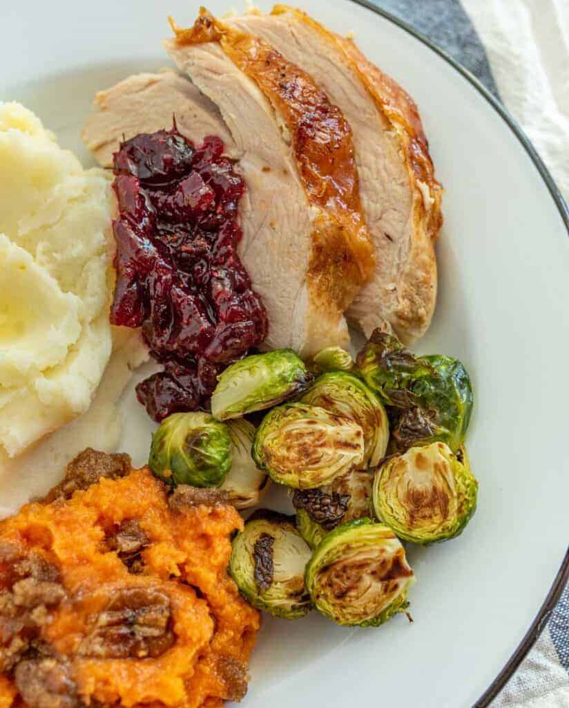 ham mashed potatoes brussel sprouts on a white dish