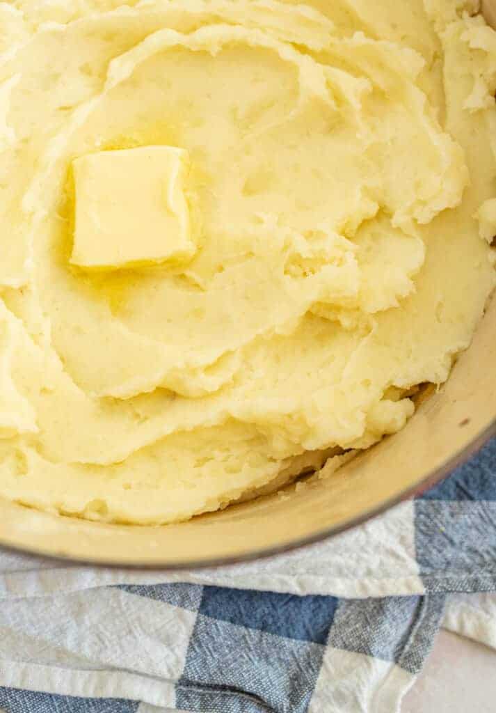 close up of mashed potatoes with butter in a red bowl
