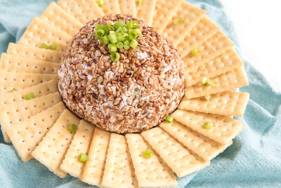 meat and onion cheese ball in the center of a plate with butter crackers all around.