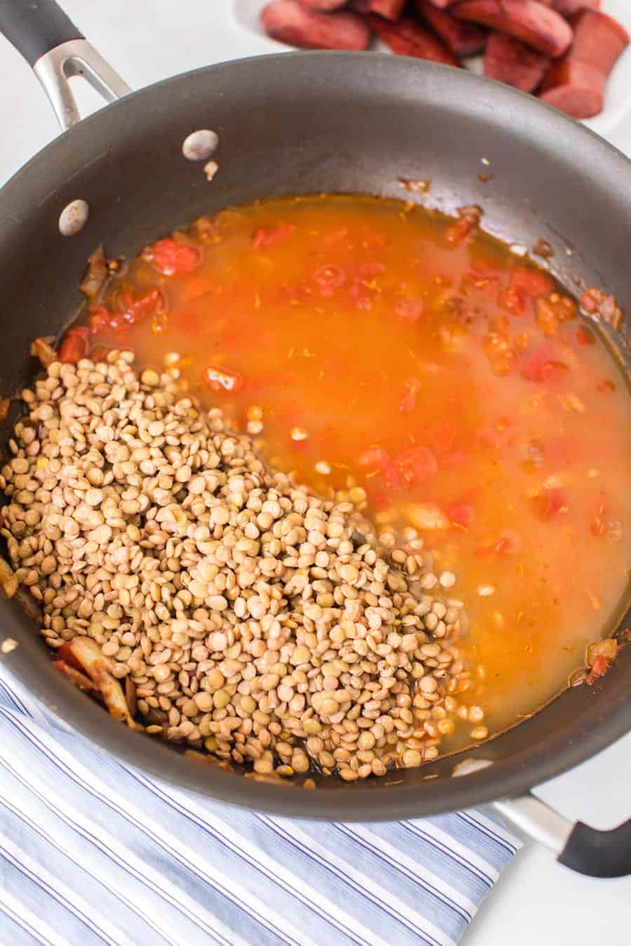 lentils and a tomato and spicy looking sauce in a pan.