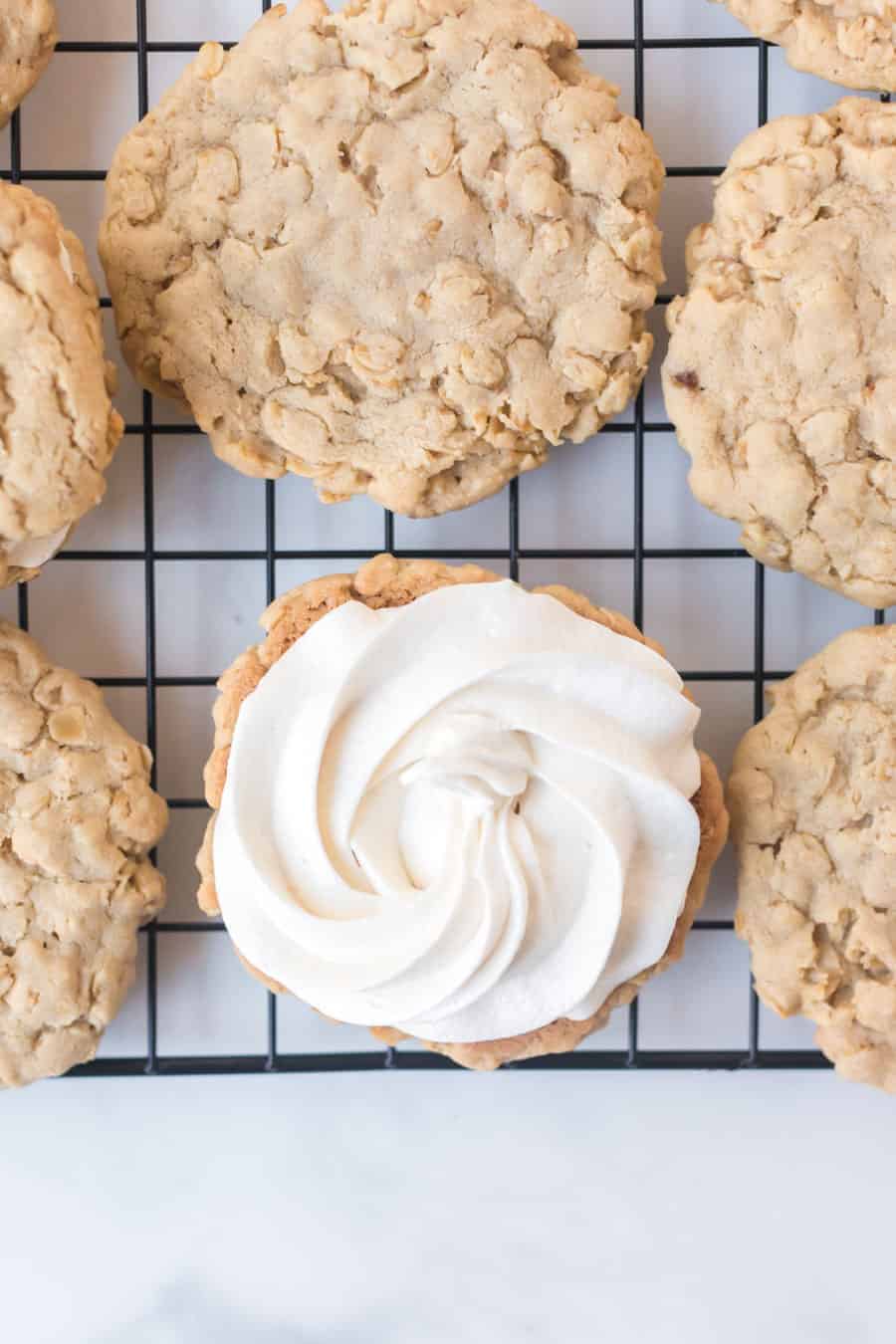 oatmeal cookies on cooling rack and one has been frosted.