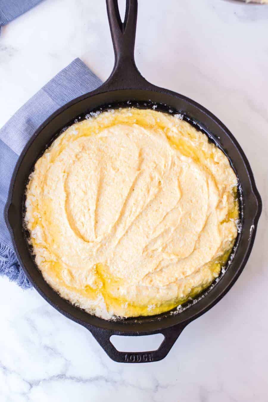 top view of raw cornbread dough in a cast iron skillet.