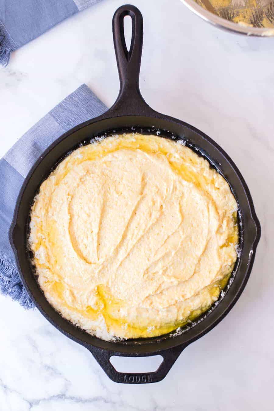 top view of raw cornbread dough in a cast iron skillet.