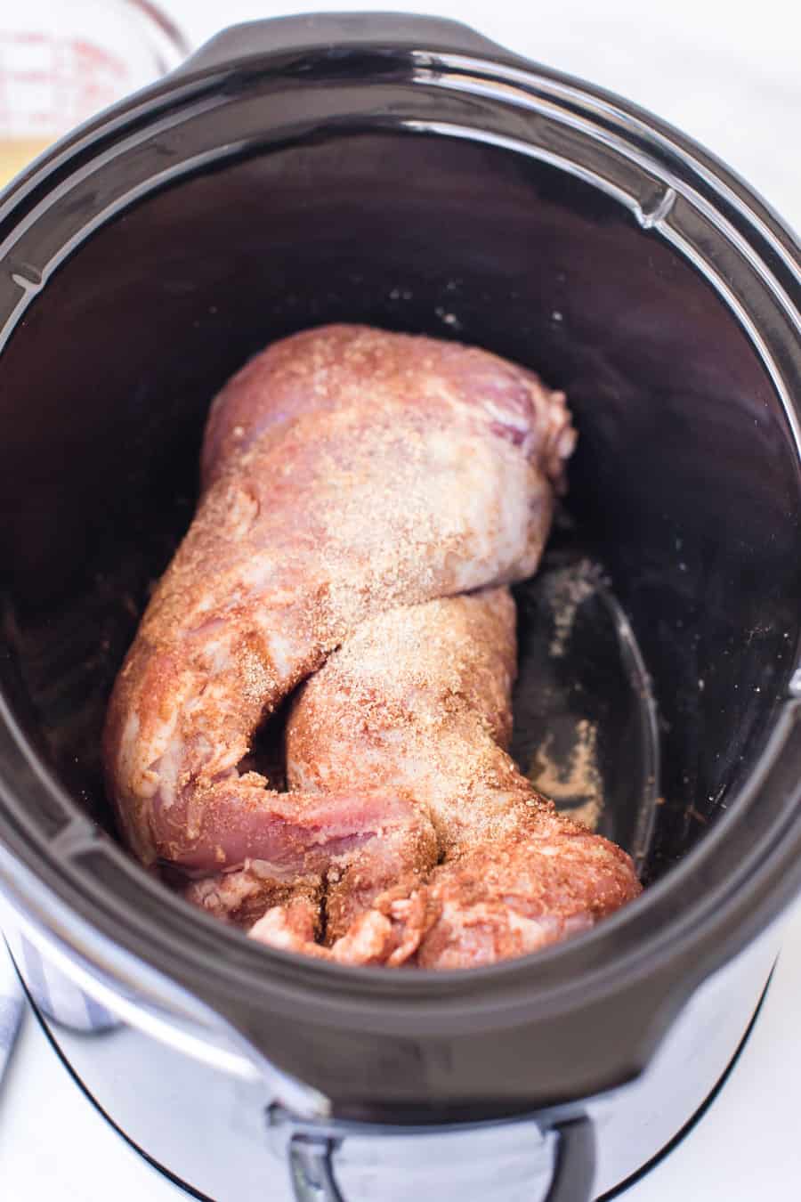 raw pork tenderloin in a crock pot before shredding.