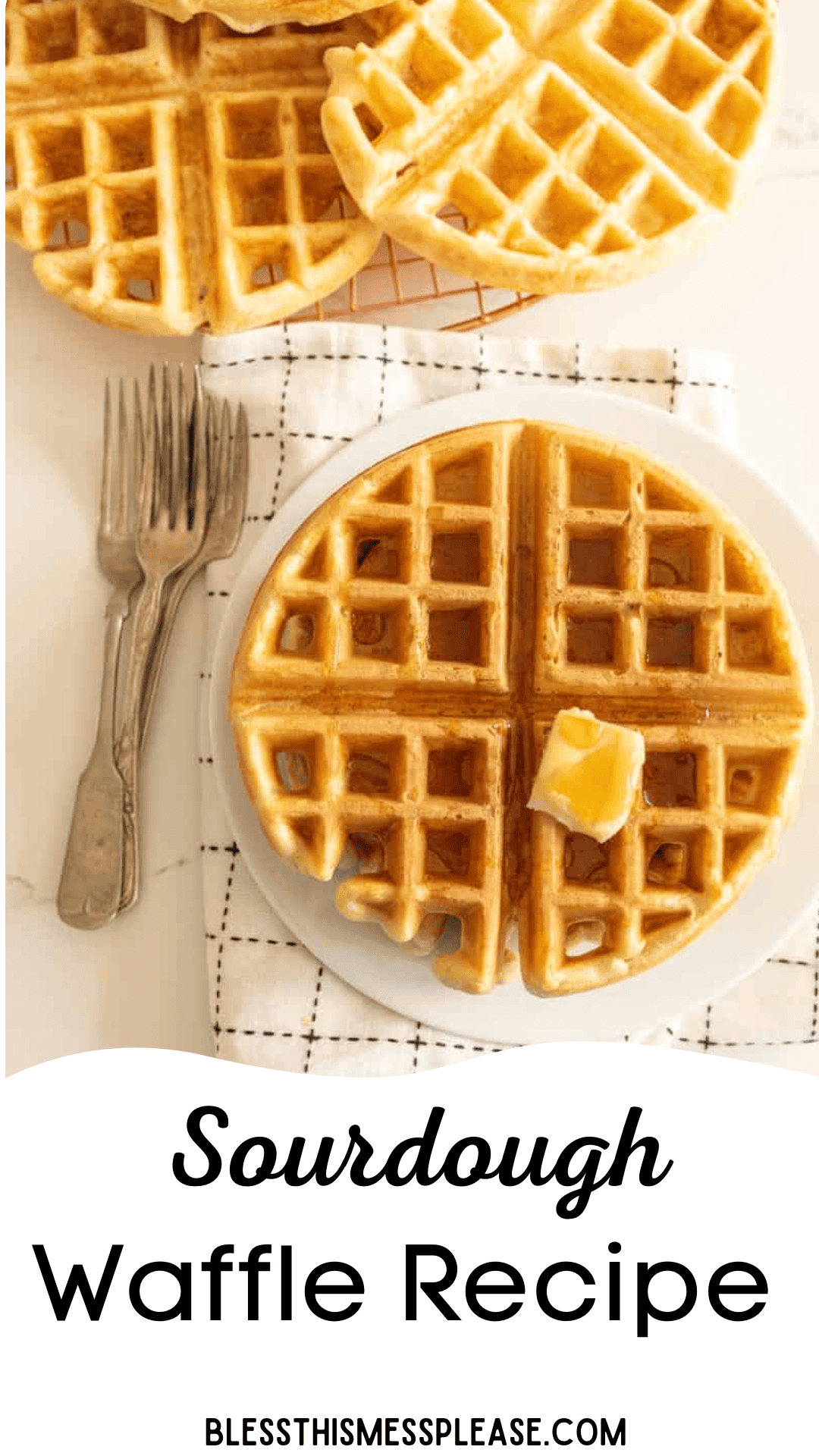 A plate with two sourdough waffles, one crowned with a pat of butter. Two forks rest beside on a cloth napkin. More waffle pieces peek from the top. Text reads Irresistible Sourdough Waffle Recipe and blessthismessplease.com.