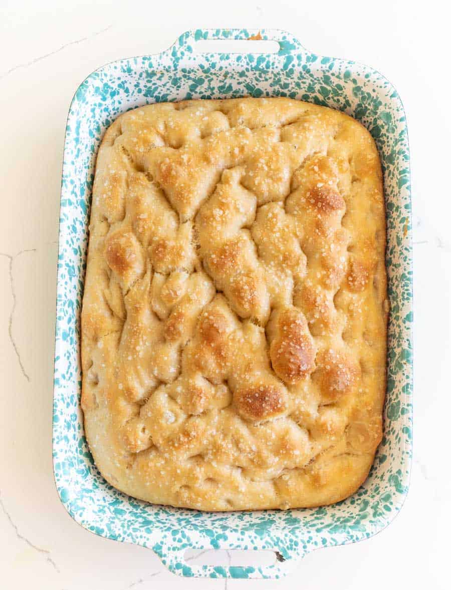 baked sourdough focaccia in pan sprinkled with salt.