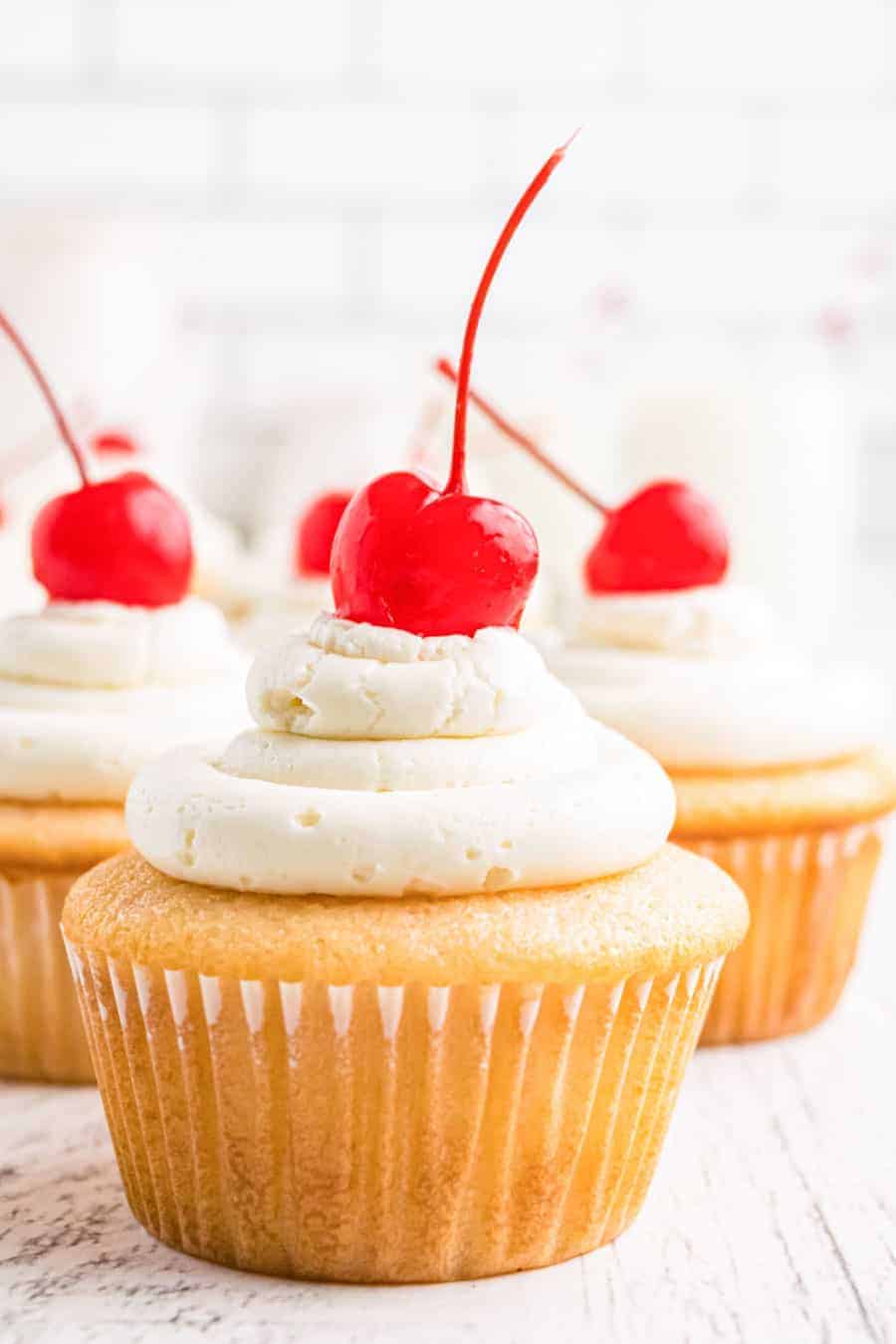 cluster of close up cherry chip cupcakes with maraschino cherries on top of each on