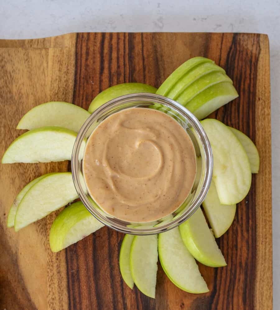 green apple slices around bowl of peanut butter dip.