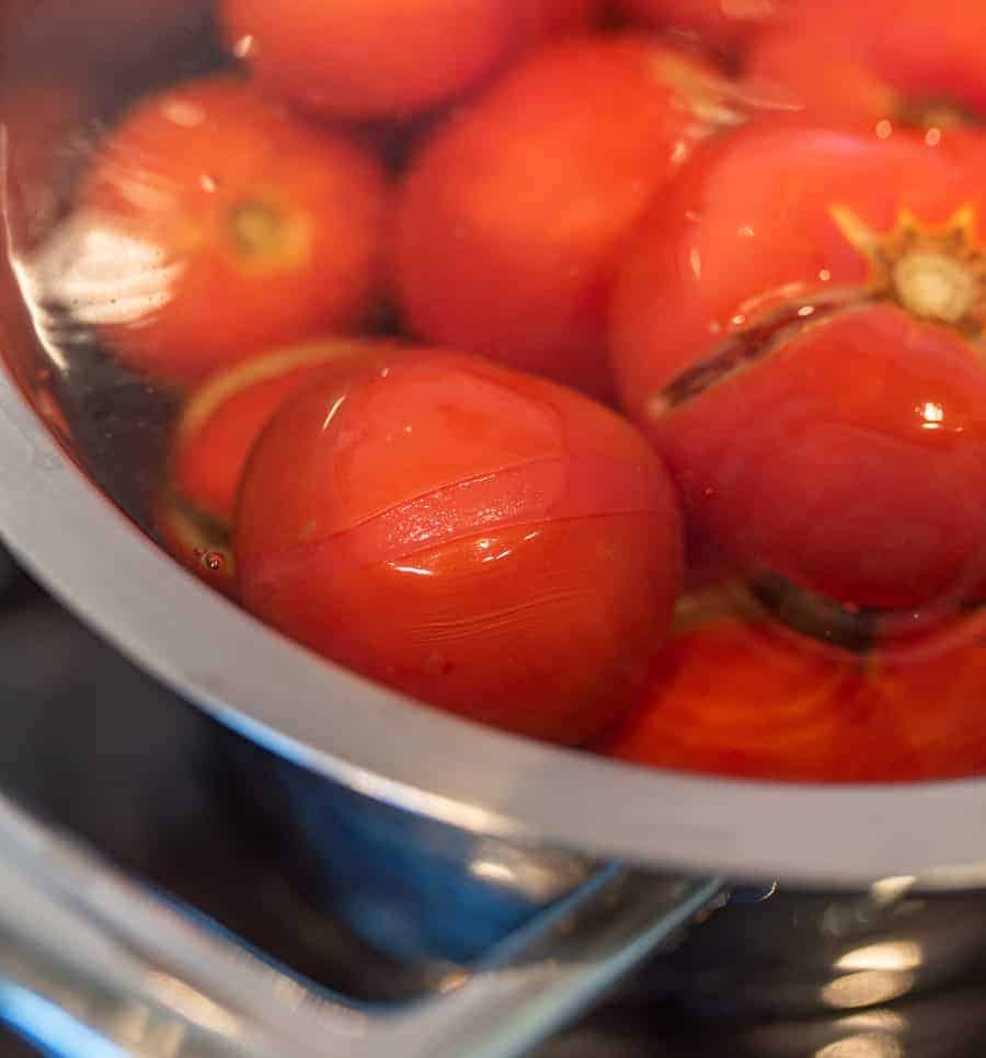 Fresh tomatoes in a pot of boiling water being balanced.