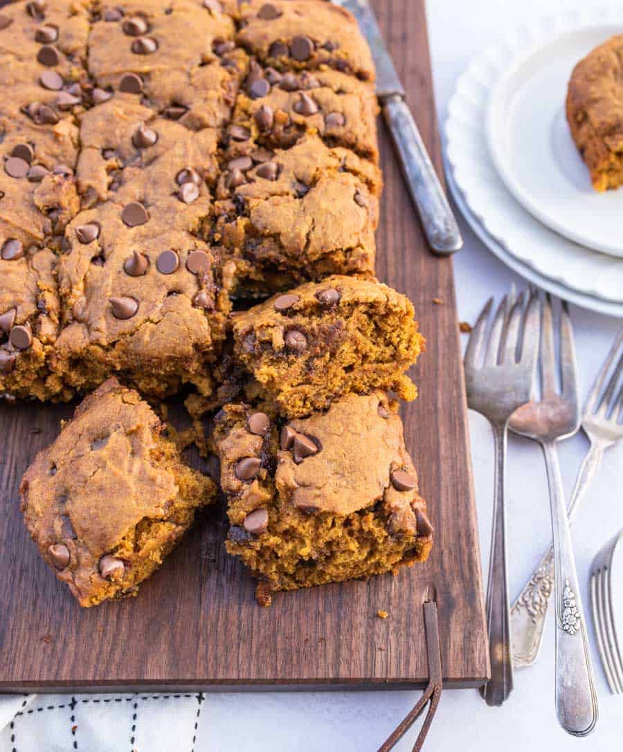 Cut chocolate chip pumpkin cake on a wooden board with a few forks next to it. 