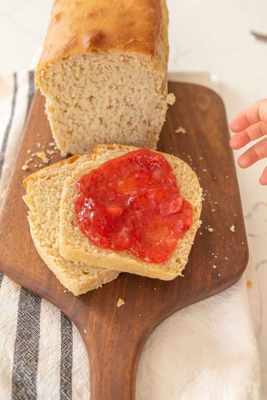 sourdough bread loaf cut into slices and jam smeared on the top of the closest slice