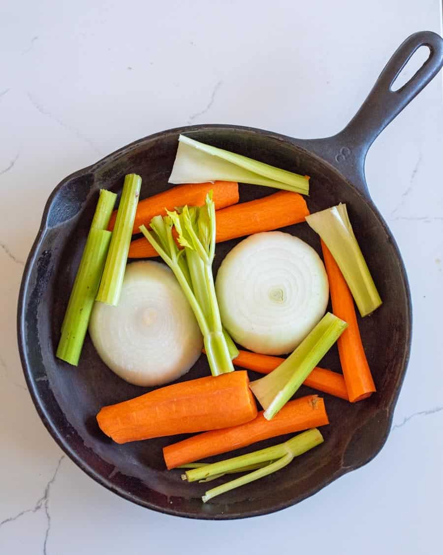 Carrots, celery, and onions roughly chopped and in the bottom of a cast iron pan. 