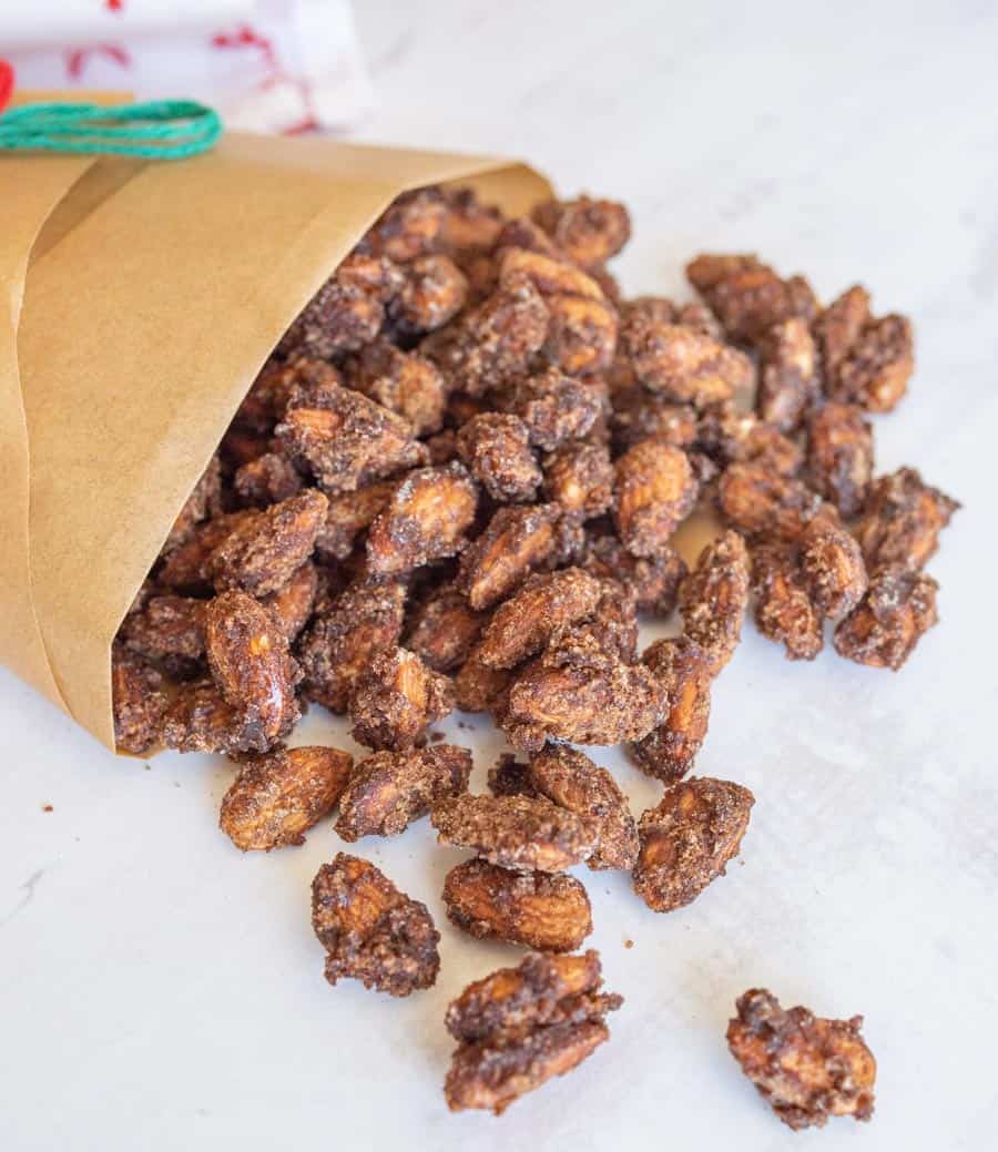 Cinnamon candied almonds spilling out of brown bag.