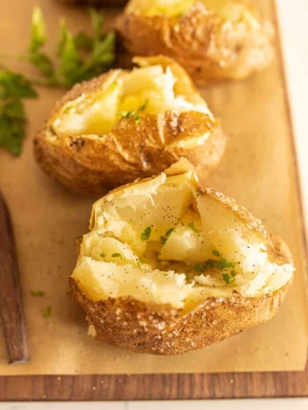 close up view of baked potato with other baked potatoes in the background