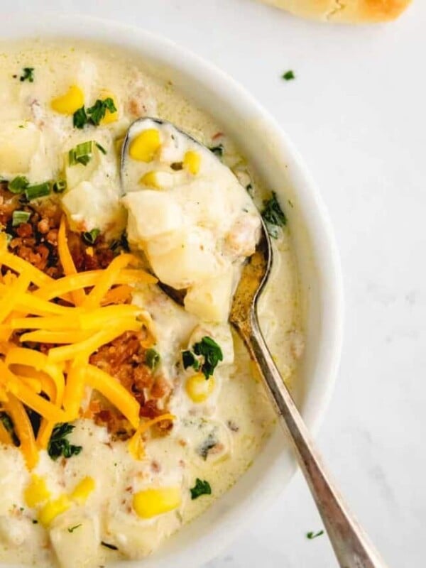 close up creamy potato soup with an instant pot in the background and garnished with cheddar cheese and greens